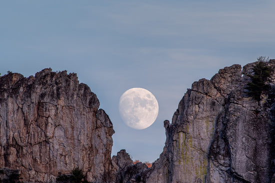 Telephoto shot of the full moon rises between the gunsight at Seneca Rocks in West Virginia
