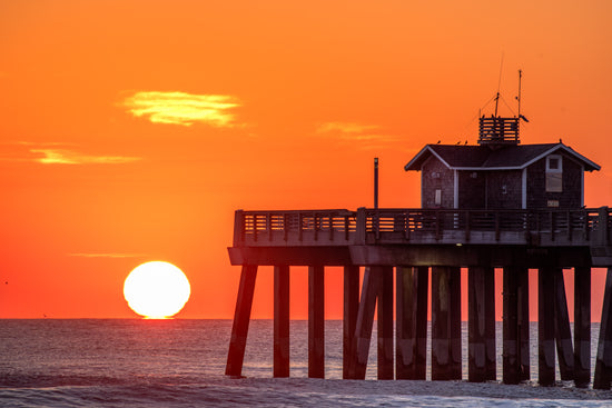 Telephoto shot of the sun rising over the horizon at the end of Jennette's Pier in the morning, Outer Banks, North Carolina
